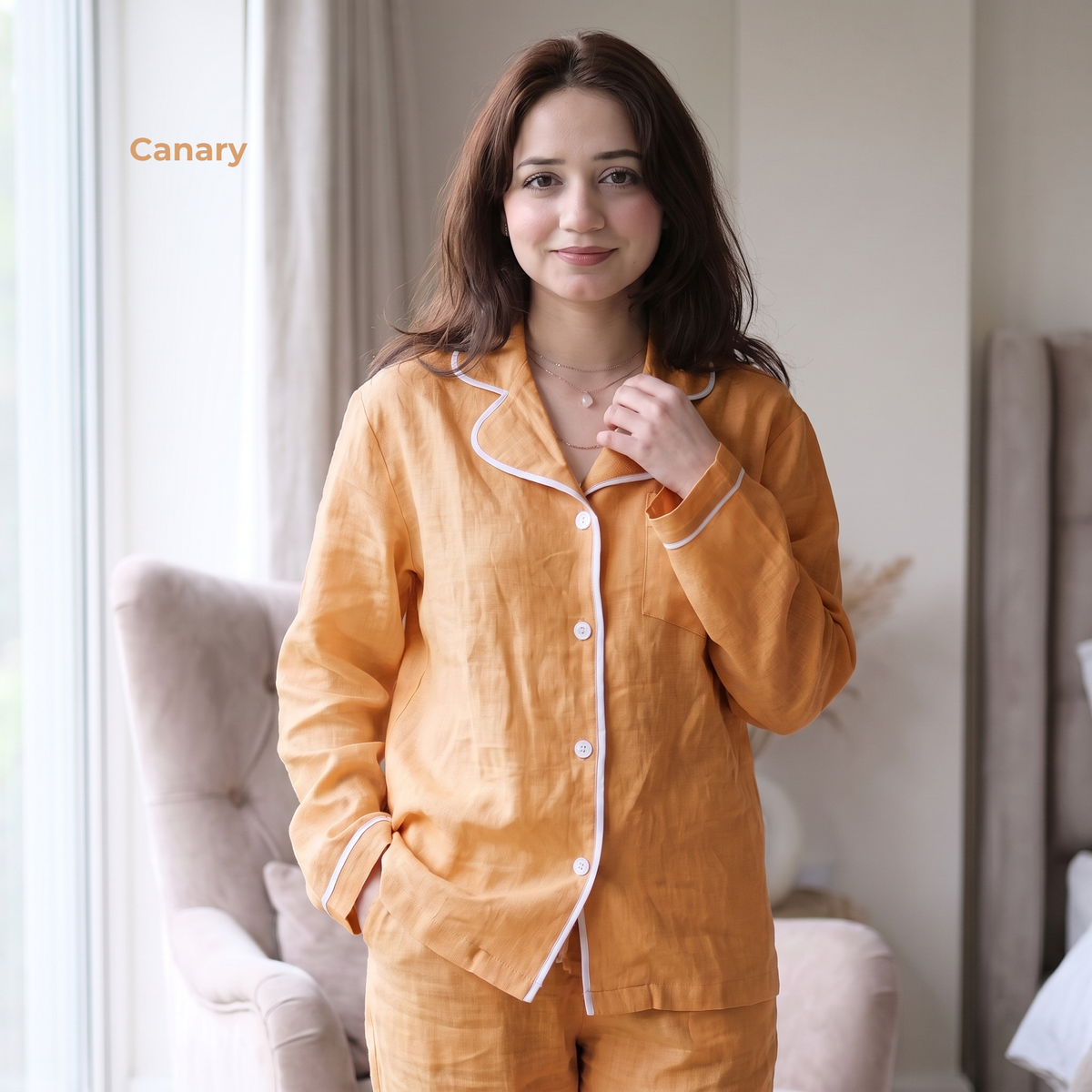 Woman wearing orange pajamas with white trim in a bedroom setting