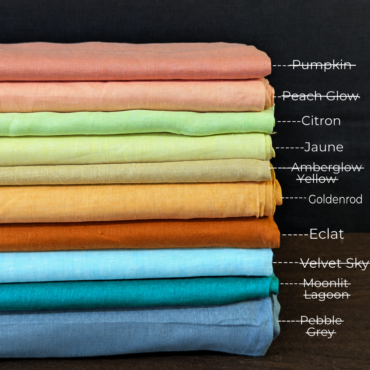 A stacked set of ten different colored fabrics, each labeled with its name on the right side, against a dark background.