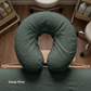 A dark green U-shaped massage pillow labeled 'Deep Pine' resting on a wooden massage table, with spa chairs and bottles visible in the background on a wood floor.