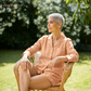 Woman in peach pajamas sitting outdoors with 'PeachGlow' branding.