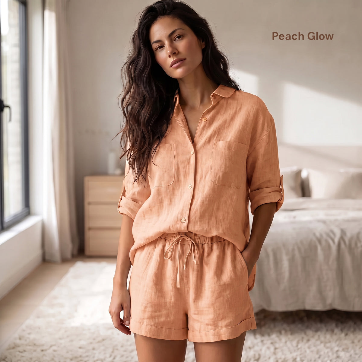A woman stands in a softly lit bedroom wearing a peach-colored linen button-up shirt and matching shorts. The text 'Peach Glow' appears in the upper right corner.